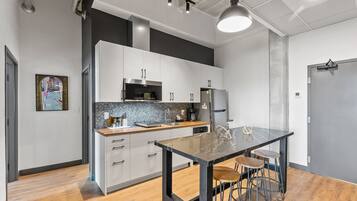 A modern kitchen with white cabinets, a black countertop, and a marble island with stools.