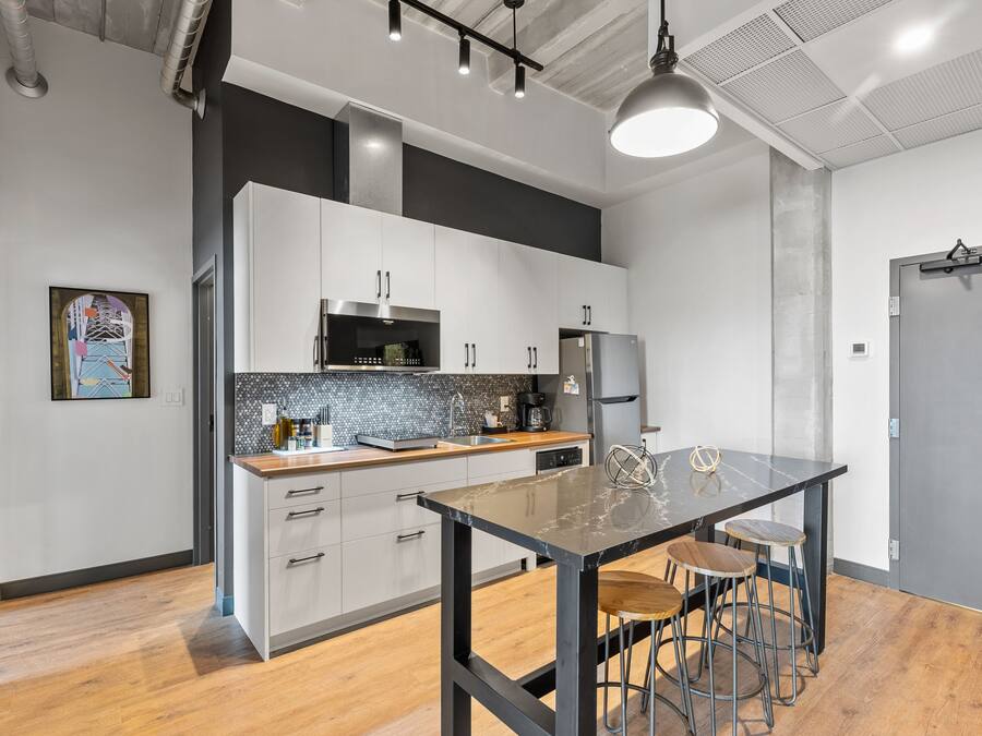 A modern kitchen with white cabinets, a black countertop, and a marble island with stools.