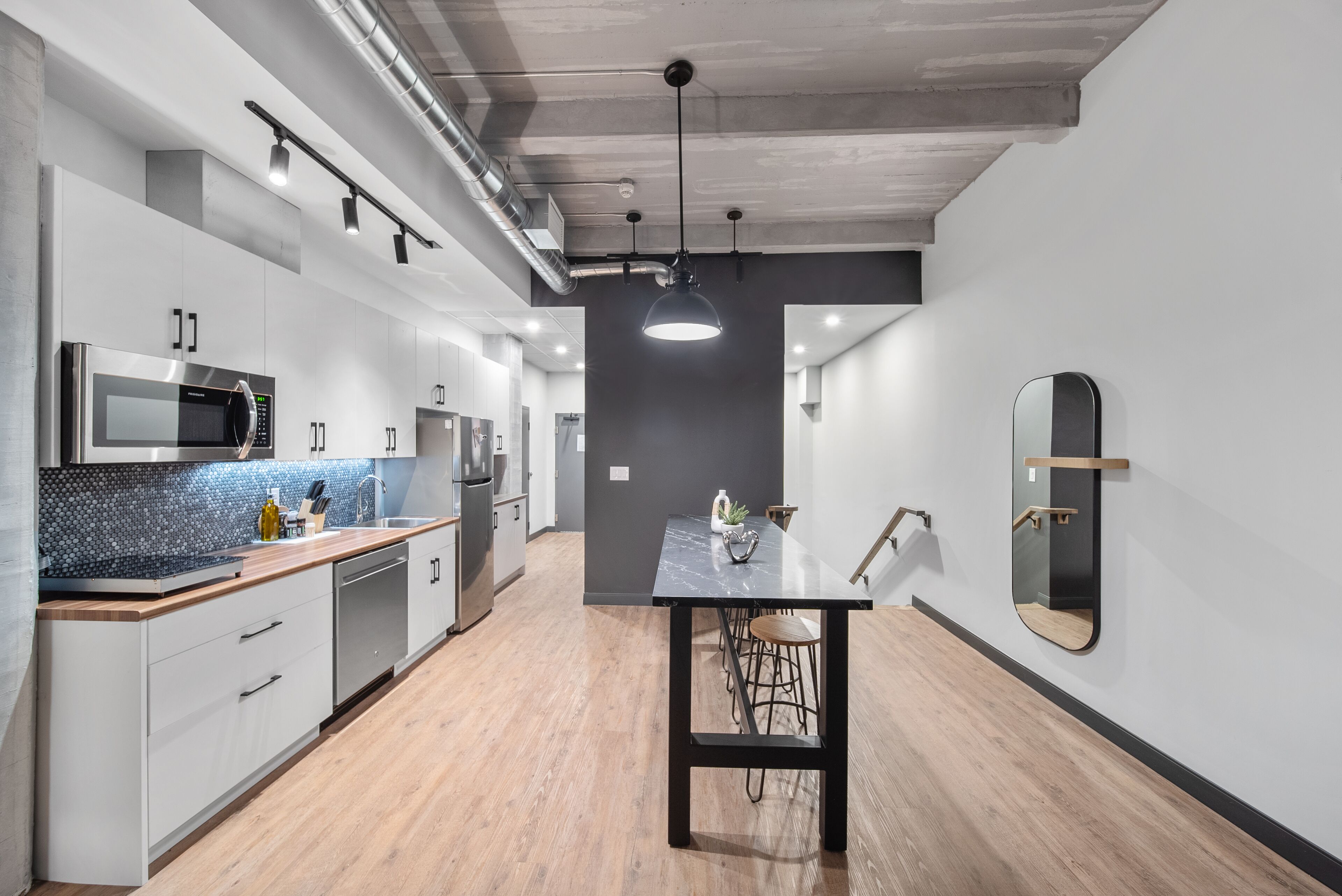 Una cocina moderna con electrodomésticos de acero inoxidable, encimera de madera y comedor con mesa y sillas.