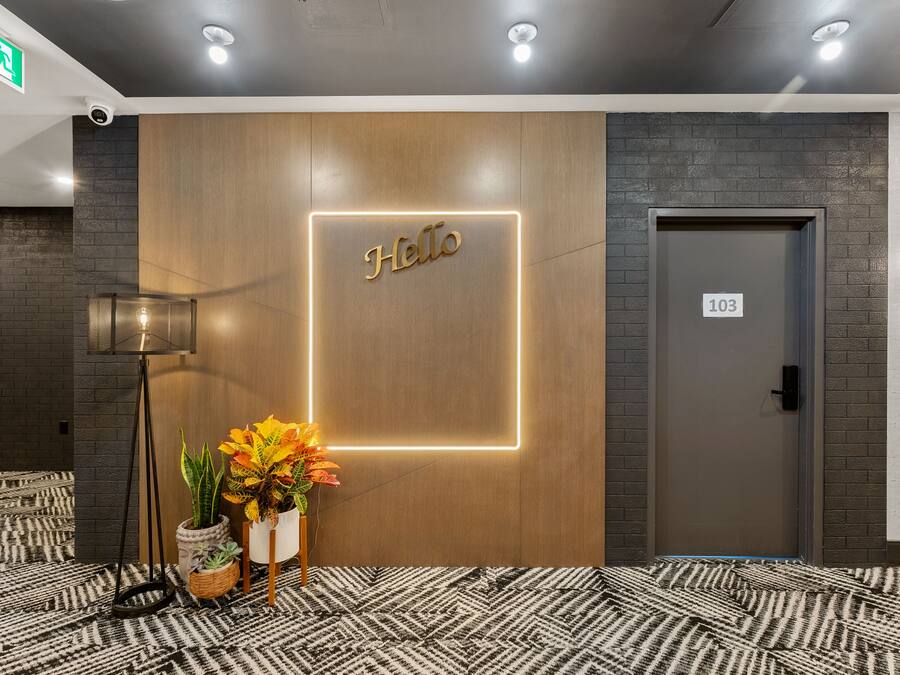 A reception area with a 'Hello' sign, a potted plant, and a door labeled '103'.