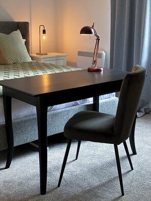 Contemporary hotel room with a bed, desk, and large window.
