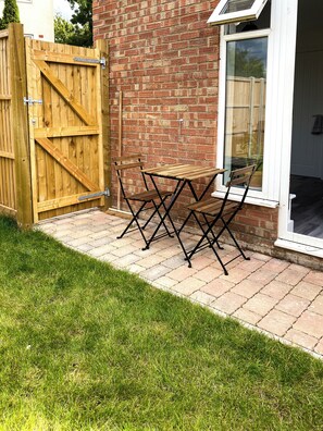 Enjoy outdoor dining or relaxation in this patio area with a table and chairs, surrounded by a well-maintained lawn.