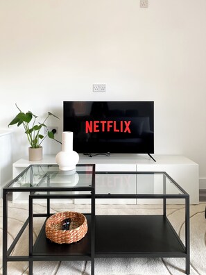Relax in this stylish living room with a flat-screen TV, coffee table, and potted plant.