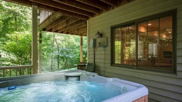 A hot tub under a wooden deck with a view of a forest. - Longwood Hideaway - A Warm, Elegant Retreat for Rest & Restoration (Galena)