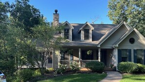 A two-story house with a covered porch, a chimney, and a well-maintained lawn. - Longwood Hideaway - A Warm, Elegant Retreat for Rest & Restoration (Galena)