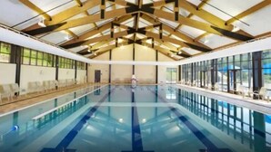 An indoor swimming pool with a high ceiling and large windows. - Longwood Hideaway - A Warm, Elegant Retreat for Rest & Restoration (Galena)