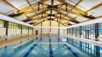 An indoor swimming pool with a high ceiling and large windows.