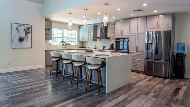 A modern kitchen with a central island, bar stools, stainless steel appliances, and pendant lighting. - Little Ranches Retreat in the Heart of Equestrian Community  (Wellington)