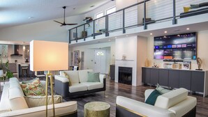A spacious living area with a high ceiling, a fireplace, and a modern entertainment unit. - Little Ranches Retreat in the Heart of Equestrian Community  (Wellington)