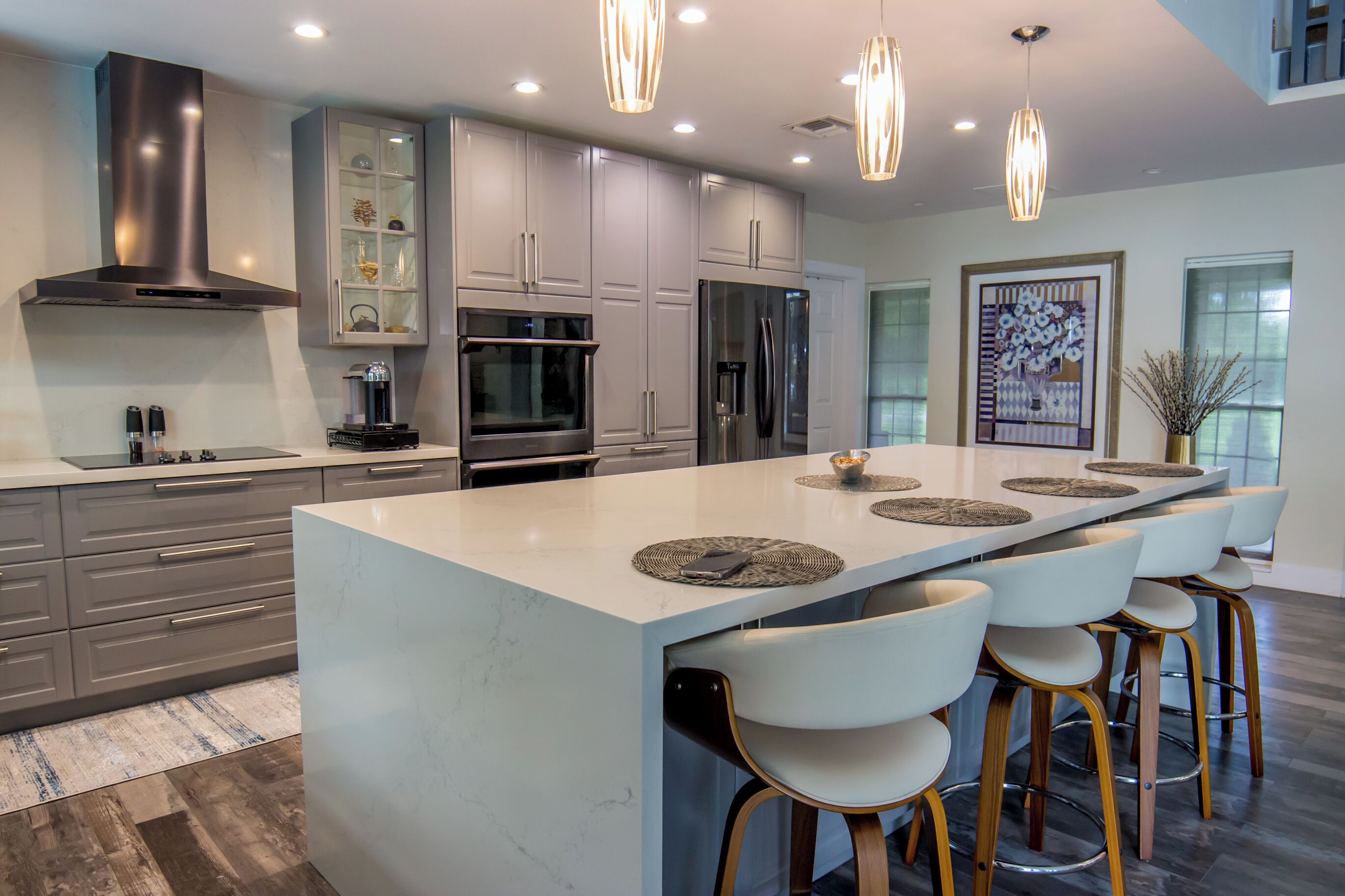 Una cocina moderna con una isla grande, electrodomésticos de acero inoxidable e iluminación colgante.