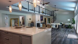 A spacious kitchen with a large island, a dining area with a high ceiling and a staircase leading to an upper level. - Little Ranches Retreat in the Heart of Equestrian Community  (Wellington)