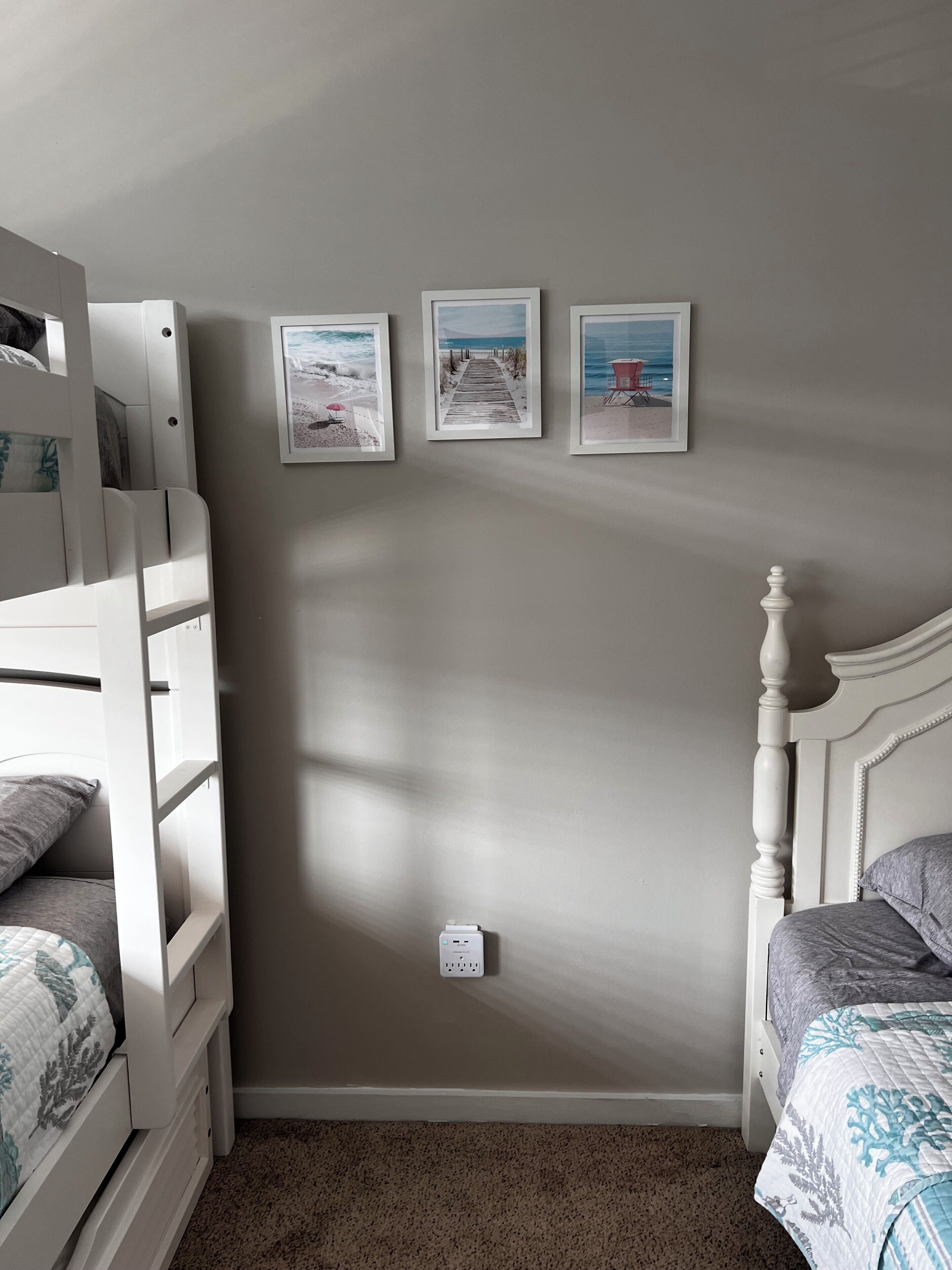 Un dormitorio con una cama litera, una cama individual y tres cuadros en la pared.