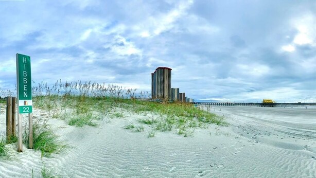 Une plage avec un panneau indiquant « Hibben 22 » et un grand immeuble en arrière-plan.