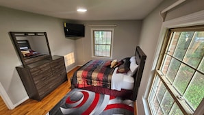 A bedroom with a bed, dresser, TV, window, and a view of greenery outside. - Gorgeous model single family home, fully renovated and ready for you.  (Newport News)