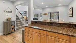 A spacious kitchen with granite countertops, wooden cabinets, and a central island. - Renovated Cottage w/ Heated Pool, Spa & Amenities! (Corolla)
