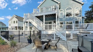 A two-story house with a balcony, a patio with outdoor furniture, and a grill. - Renovated Cottage w/ Heated Pool, Spa & Amenities! (Corolla)