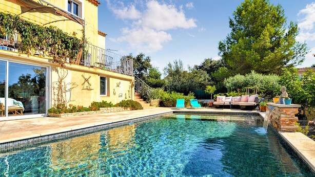 A swimming pool with clear water, surrounded by a patio area with lounge chairs and a small waterfall feature. - Stunning home in Beaucaire (Beaucaire)