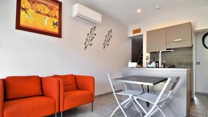 A compact living space with a sofa, a dining table with chairs, a kitchen area, and a wall-mounted air conditioner. - Stunning home in Beaucaire (Beaucaire)