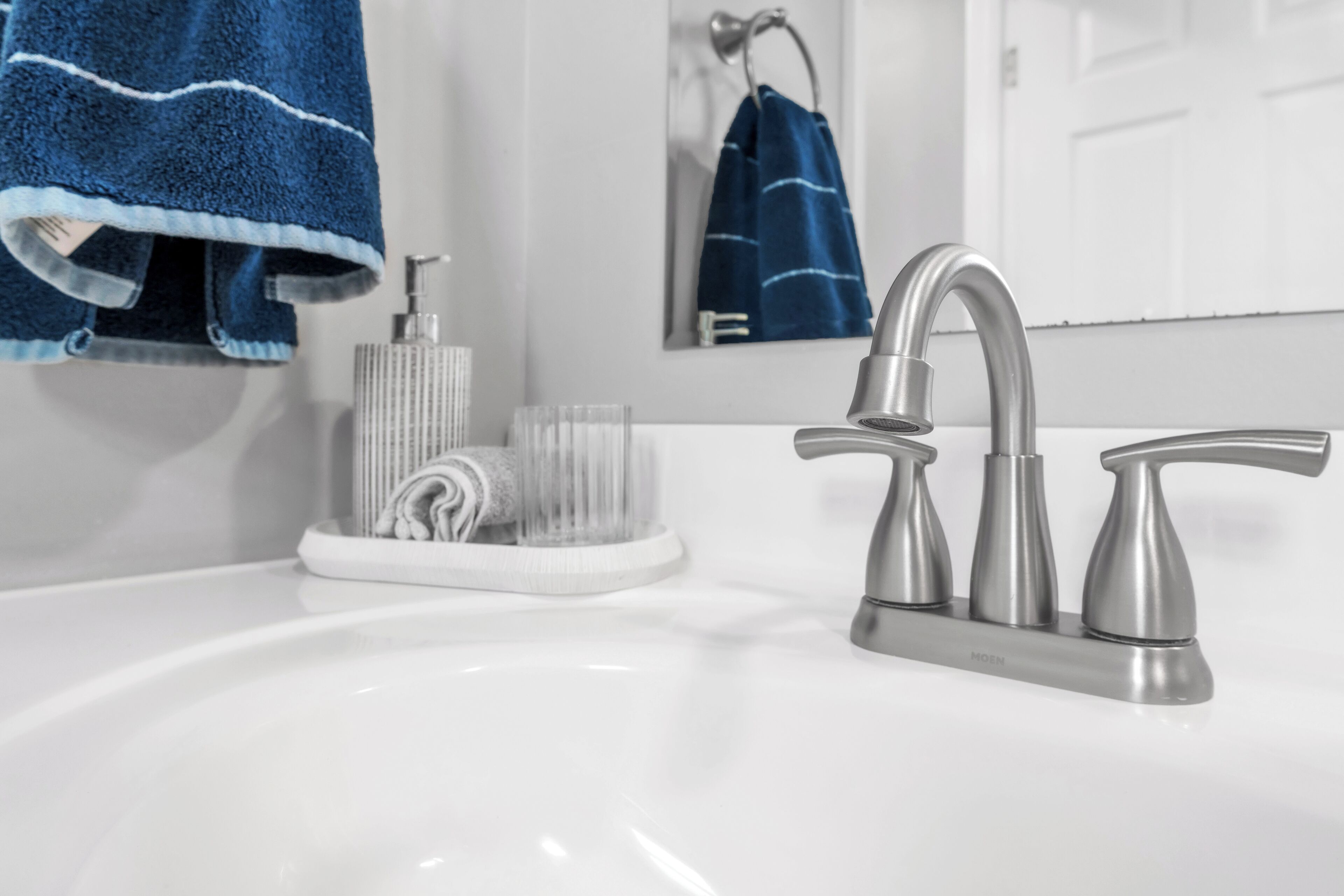 A bathroom with a white sink, a modern faucet, and a towel rack with a blue towel.