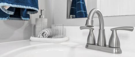 A bathroom with a white sink, a modern faucet, and a towel rack with a blue towel.