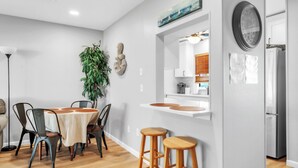 Una cocina moderna con armarios blancos, un refrigerador de acero inoxidable y una mesa de comedor de madera con sillas.