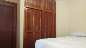 A bedroom with a wooden wardrobe, a bed with white bedding, and a white pillow. - Hotel RustiCall (La Paz)