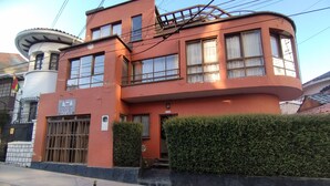 A multi-story building with a red facade, a gated entrance, and a small balcony. - Hotel RustiCall (La Paz)