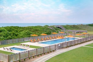 Relax by the pool with ocean views, lounge chairs, and umbrellas.