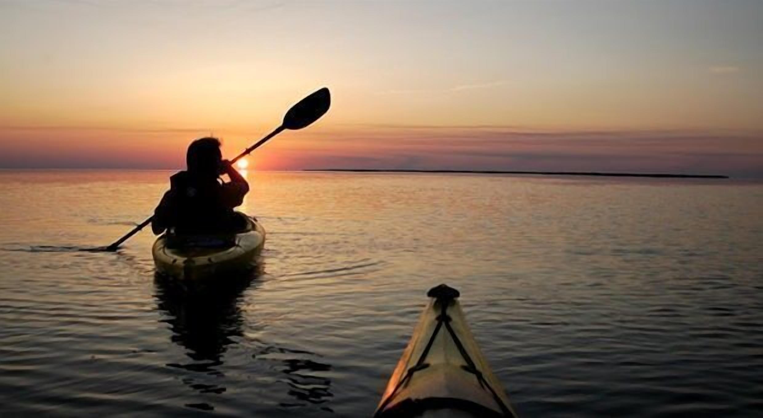 A kayak on calm water during sunset.
