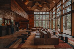 A spacious lobby with a wooden ceiling, large windows, a seating area, and a reception desk. - Get Hotel Molvento, AKEN SOUL Collection (Villa General Belgrano)
