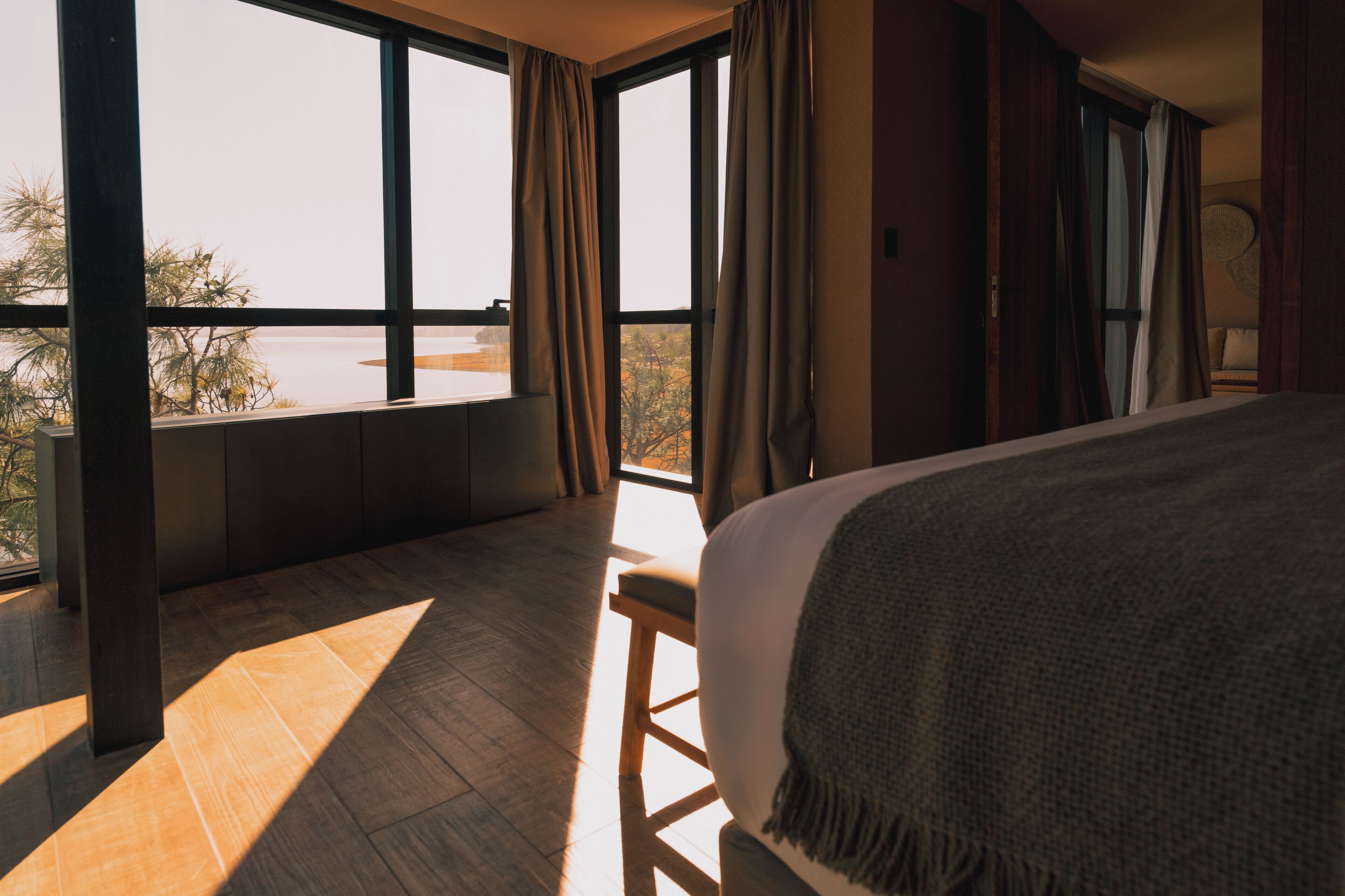 A bedroom with a large window, a bed, and a view of the outdoors.
