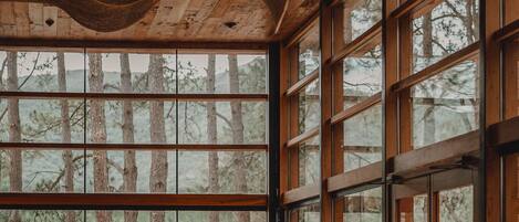 A spacious room with large windows, a wooden ceiling, and a cozy seating area.