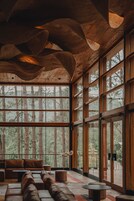 Una habitación amplia con ventanas grandes, techo de madera y un rincón de estar acogedor.