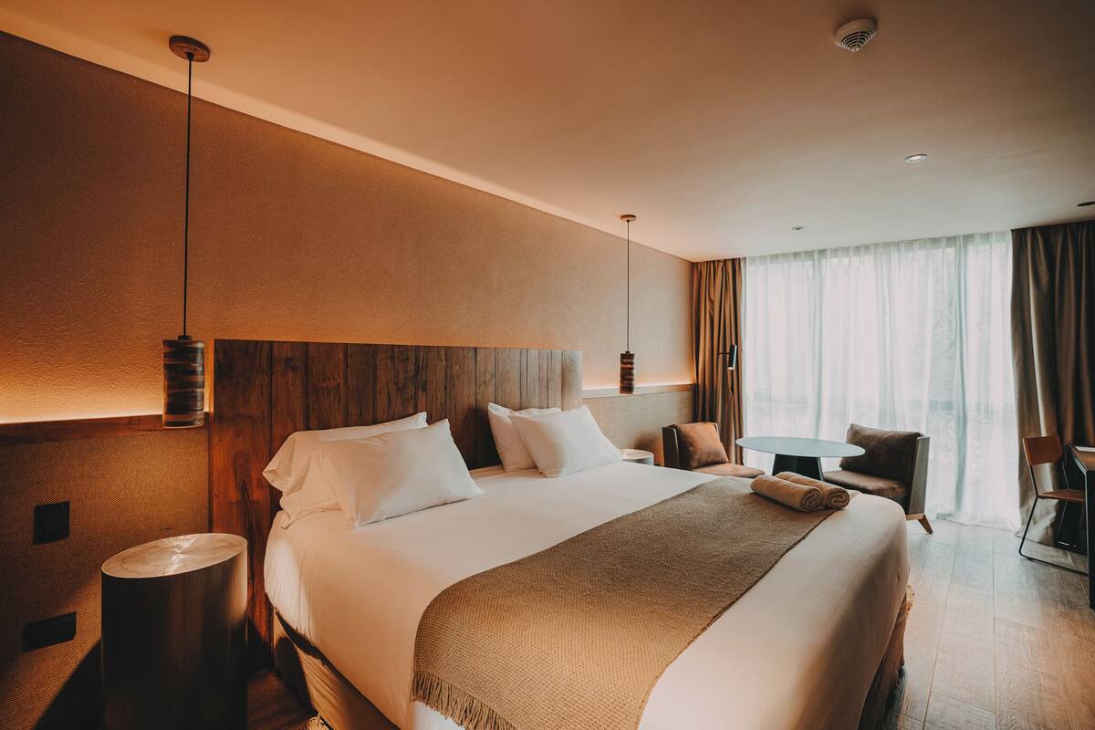 A hotel room with a large bed, bedside tables, a desk, and a chair.