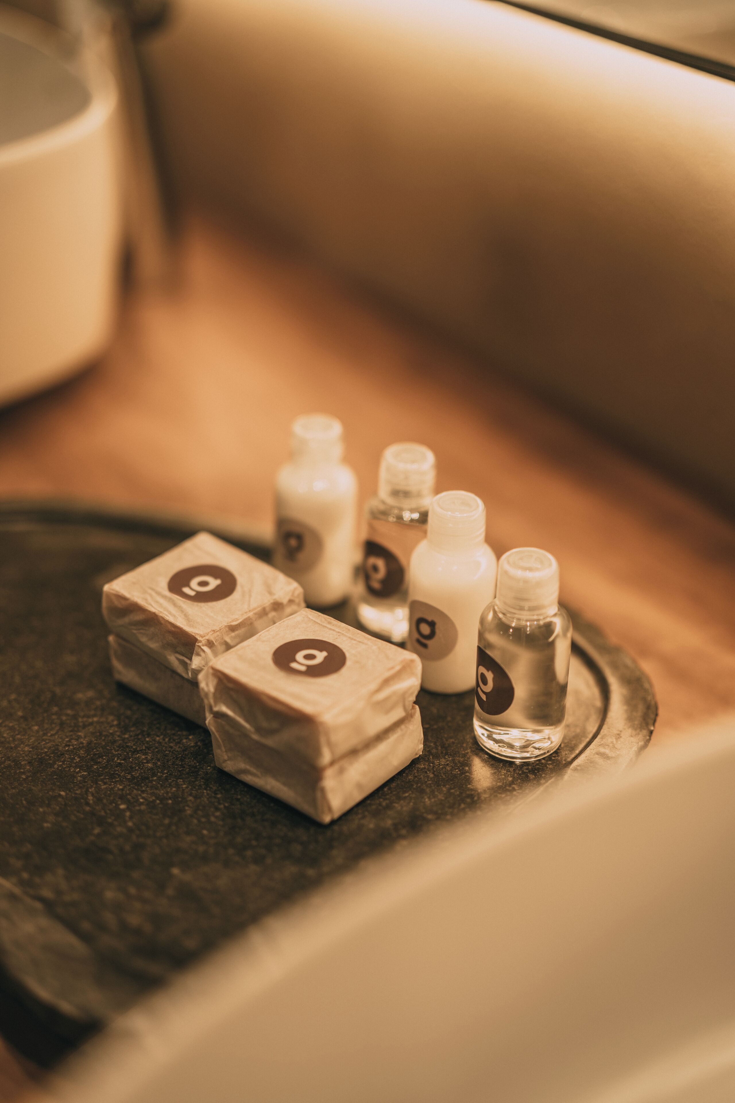 A tray with several small bottles and wrapped items, likely toiletries, on a metallic surface.