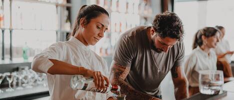 Um bar com um bartender preparando uma bebida.