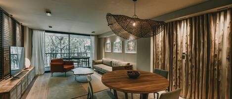 A modern living room with a round wooden table, a sofa, and a hanging light fixture.