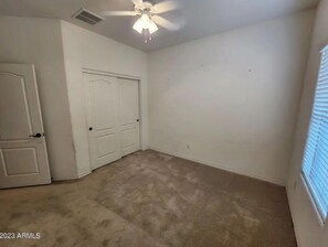Simple, well-appointed room with a door and ceiling fan.