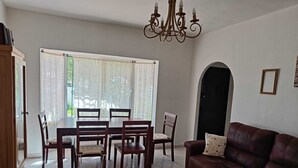 Ein Essbereich mit Tisch und Stühlen, einer Kandelaber, einer Couch und einer Tür zu einem anderen Raum.