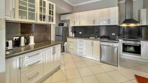 A modern kitchen with white cabinetry, stainless steel appliances, and a tiled floor.