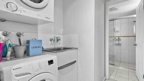 A modern laundry room with a front-loading washing machine, a dryer, and a sink. - Apt 3 Brightside Apartments - City Center (Armidale)