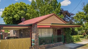 A small brick house with a red roof, a fenced driveway, and a satellite dish. - Apt 3 Brightside Apartments - City Center (Armidale)