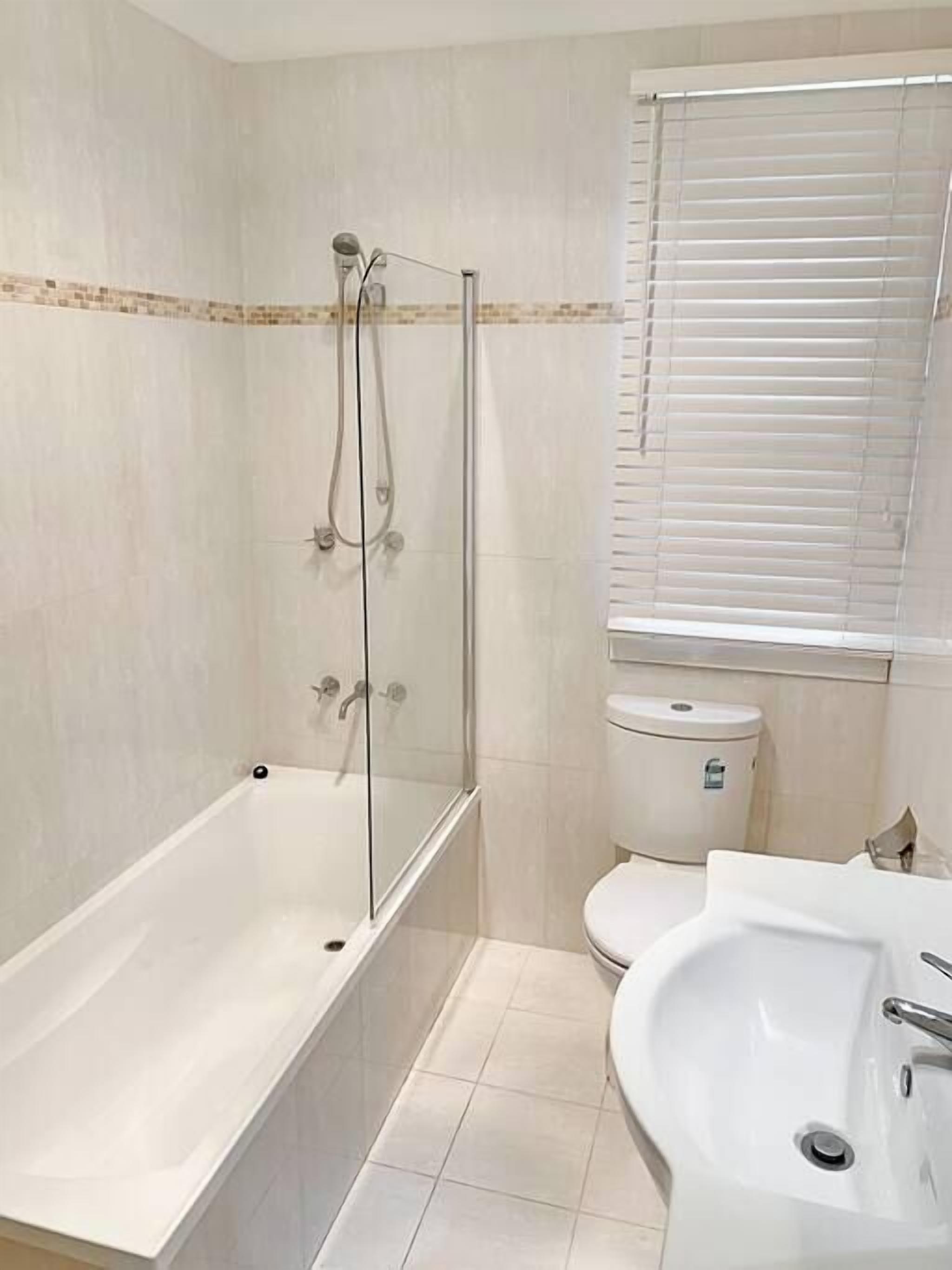 Ein Badezimmer mit einer Duschkabine aus Glas, einem weißen Waschbecken und einer Toilette.