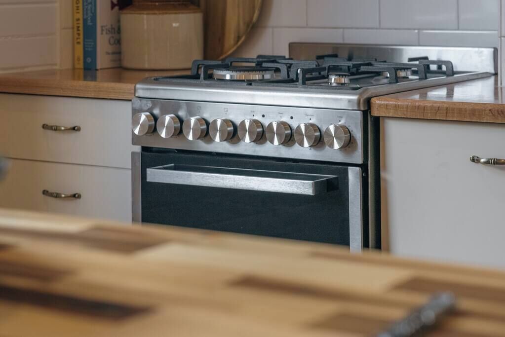 Uma cozinha com fogão de aço inoxidável, forno embutido e armários de madeira.