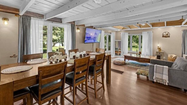A spacious living area with a wooden dining table, chairs, a sofa, and a television. - Riverfront, swimming pool, hot tub, pickleball court, basketball, billiard (Lyndon)
