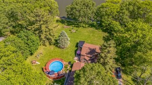 An aerial view of a property with a swimming pool, a fenced yard, and a house with a red roof. - Riverfront, swimming pool, hot tub, pickleball court, basketball, billiard (Lyndon)