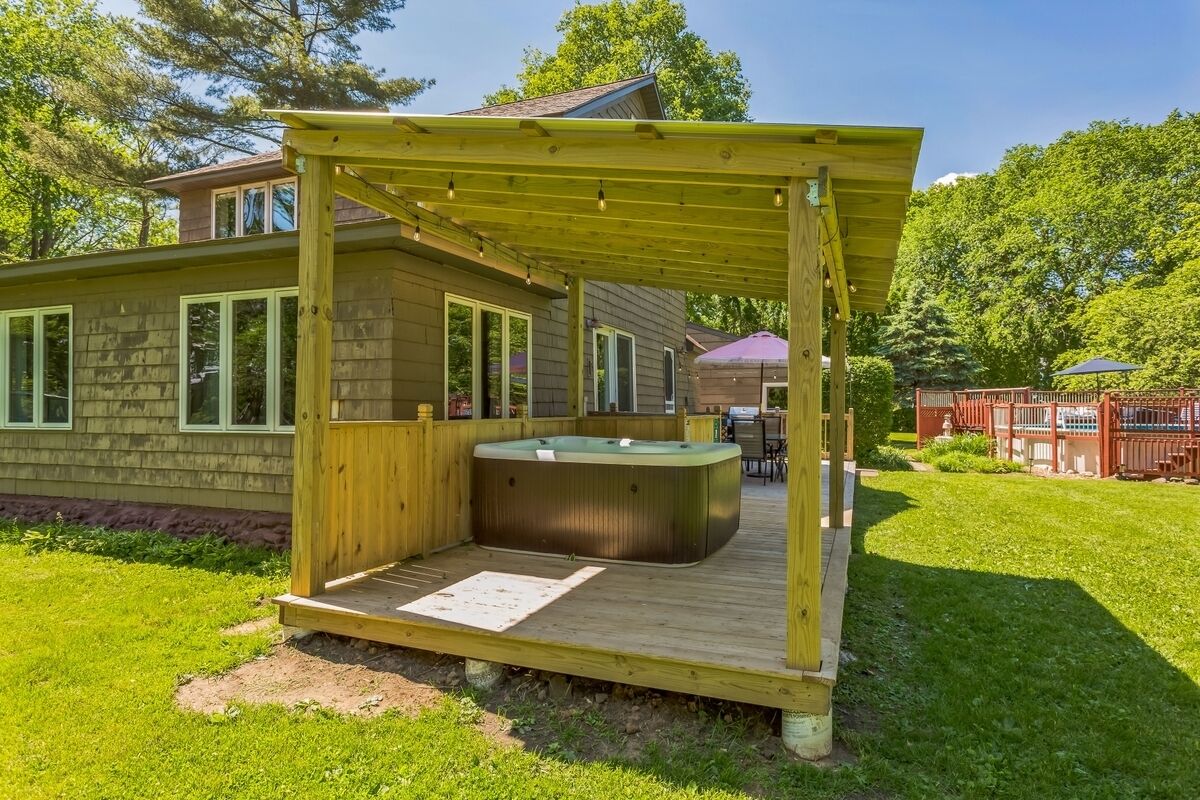 A wooden deck with a hot tub and a pergola.