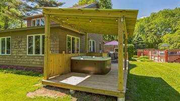 A wooden deck with a hot tub and a pergola.