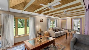 A spacious living room with a wooden ceiling, large windows, a sofa, a coffee table, and a foosball table. - Riverfront, swimming pool, hot tub, pickleball court, basketball, billiard (Lyndon)