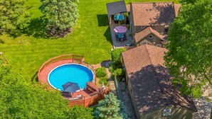 A residential property with a swimming pool, a patio with outdoor furniture, and a house with a tiled roof. - Riverfront, swimming pool, hot tub, pickleball court, basketball, billiard (Lyndon)